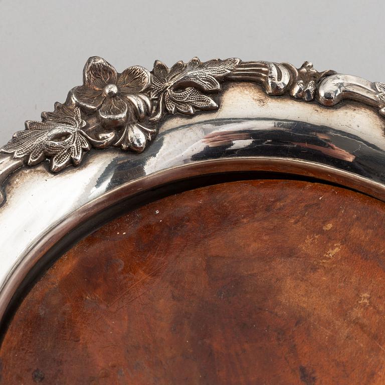 A pair of silver plate and wood coasters, circa 1900.