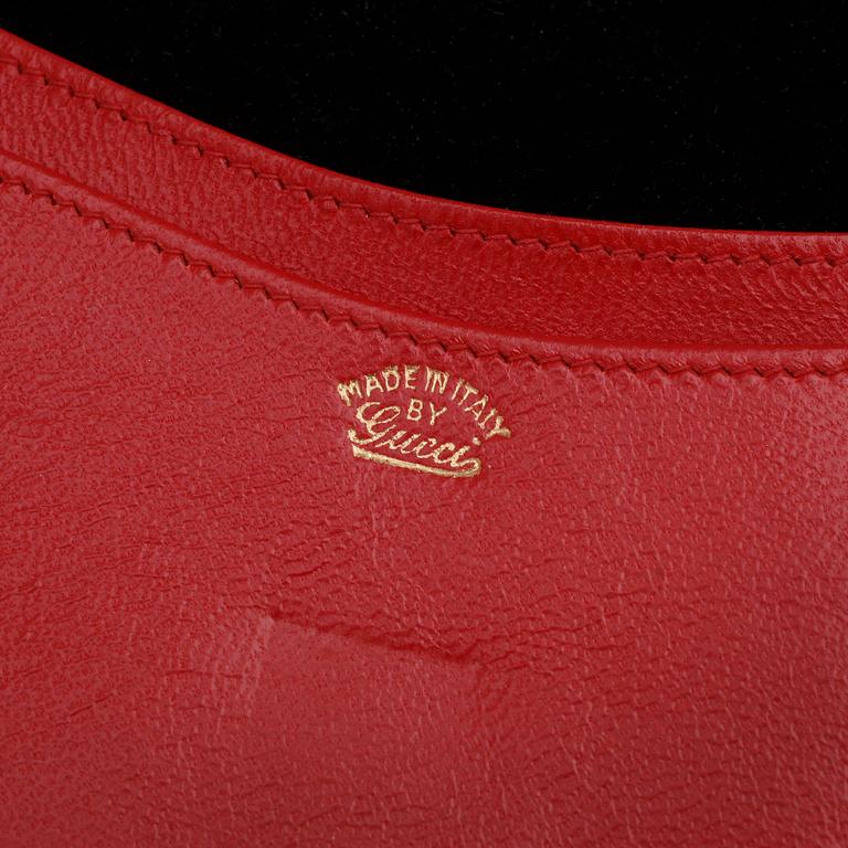 GUCCI, a black suede wallet with red leather lining.