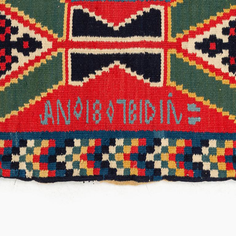 A carrige cushion, 'Träd och timglas', double-interlocked tapestry, c. 102 x 53 cm, signed BID IÅ, dated 1807.