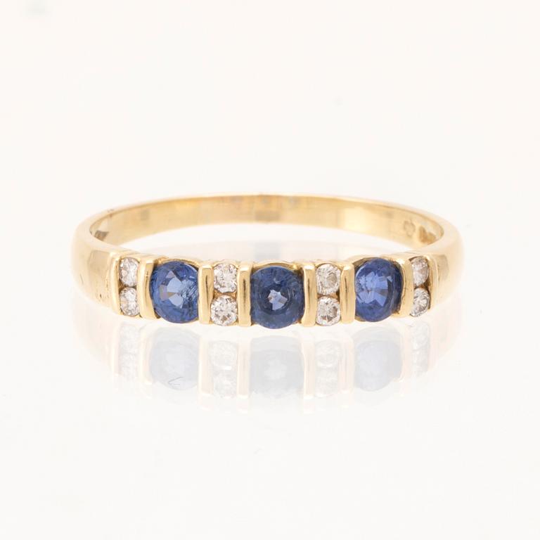 An 18K gold ring set with round brilliant-cut diamonds and round faceted blue stones, London England.