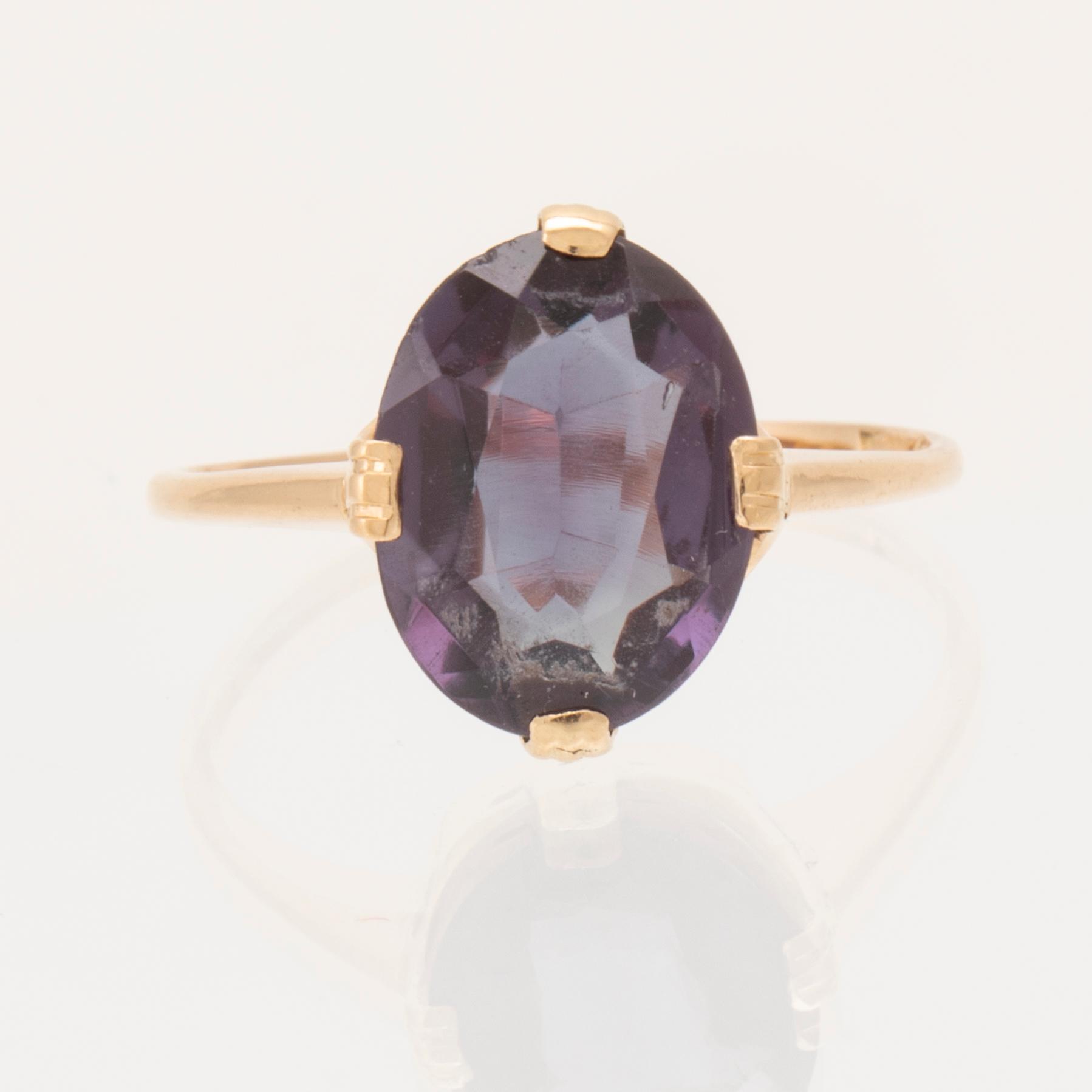 An 18K gold ring set with a synthetic colourchange purple sapphire.