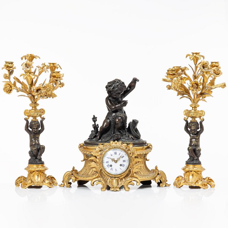 A Rococo style mantle clock and pair of candelabra, France, late 19th Century.