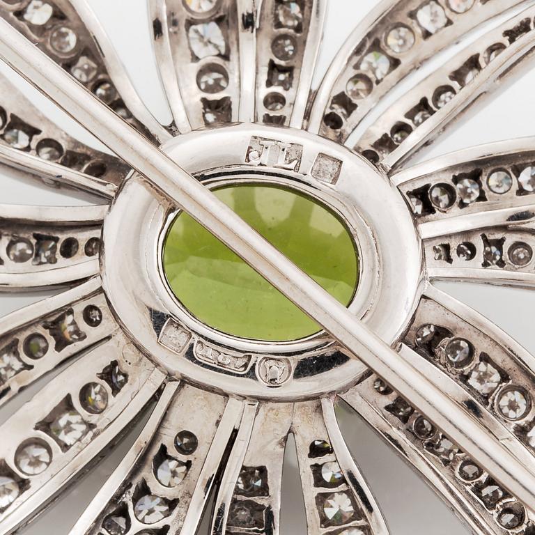 An 18K white gold brooch set with a faceted peridot and eight-cut diamonds.