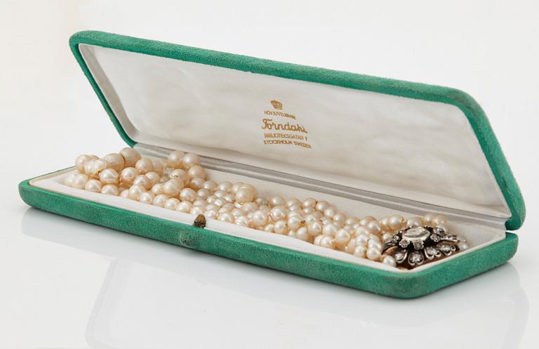 A three strand cultured pearl necklace with a clasp in 18K gold and silver set with rose- and old-cut diamonds.