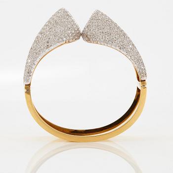 An 18K gold bangle set with round brilliant-cut diamonds.