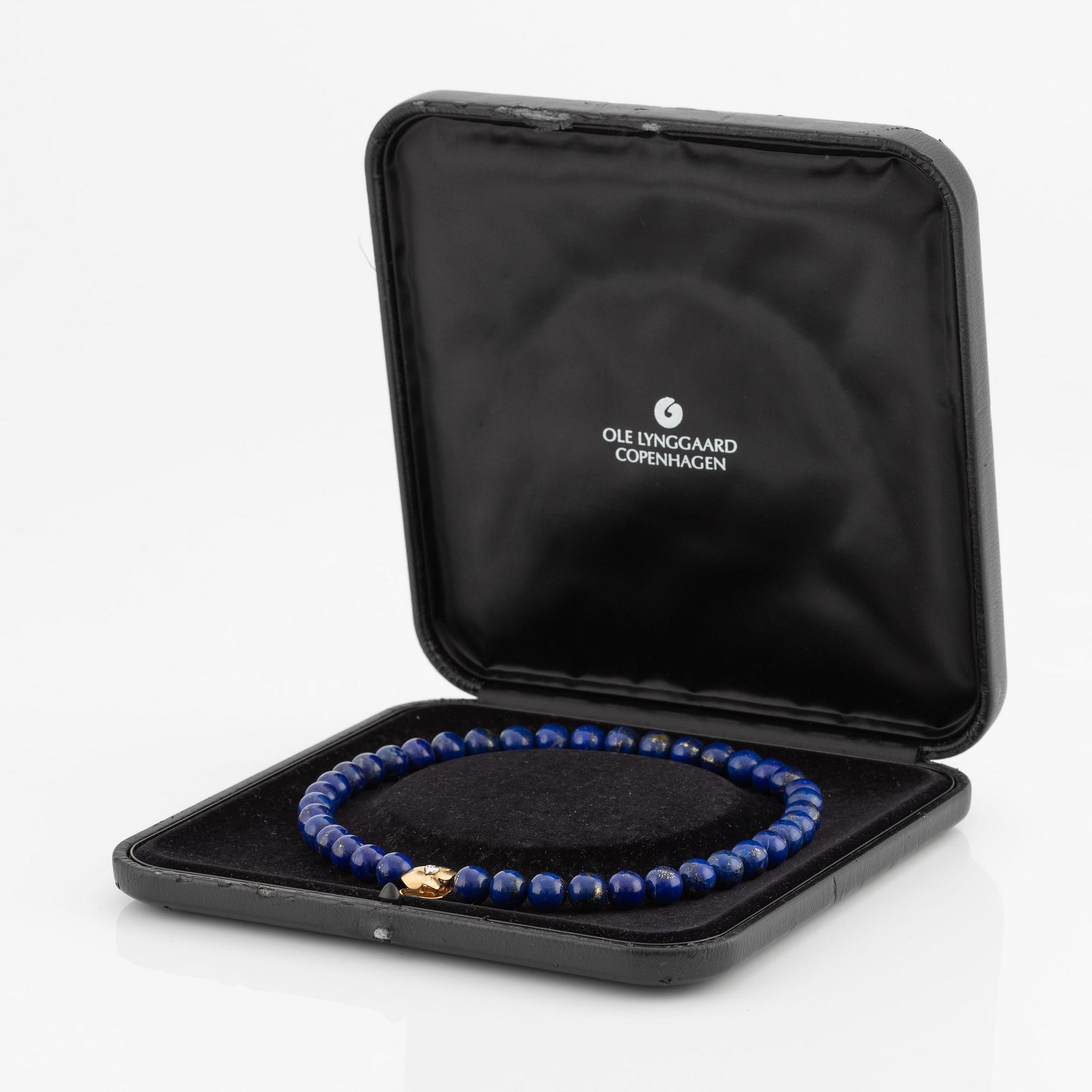 An Ole Lynggaard clasp in 18K gold with round brilliant-cut diamonds and a lapis lazuli necklace.