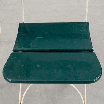 A pair of cast iron chais with wooden seats and a cast iron table, early 20th century.