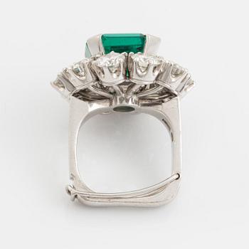 A WA Bolin platinum ring set with a step-cut emerald and round brilliant-cut diamonds.