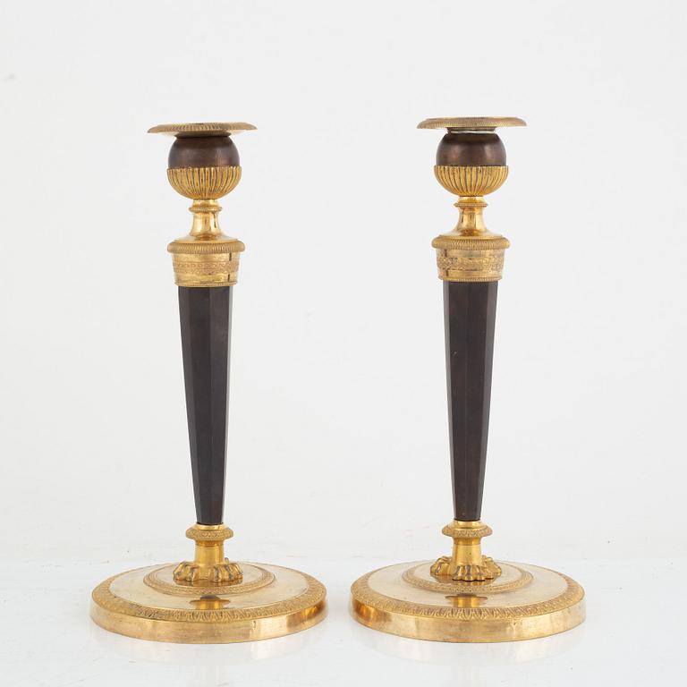 A pair of French gilt and patinated bronze Empire candlesticks, early 19th century.