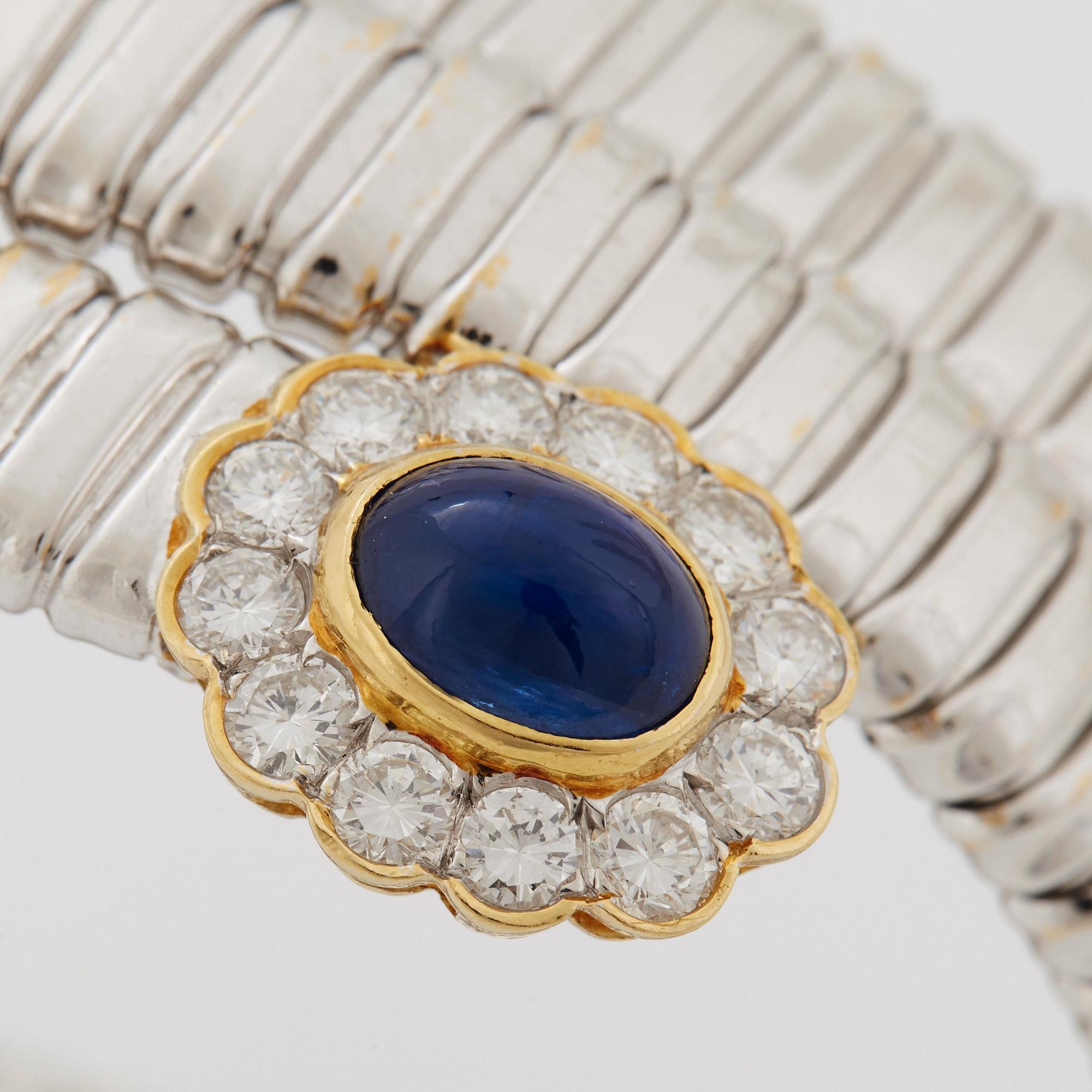 An 18K gold bangle set with cabochon-cut sapphires and round brilliant-cut diamonds.