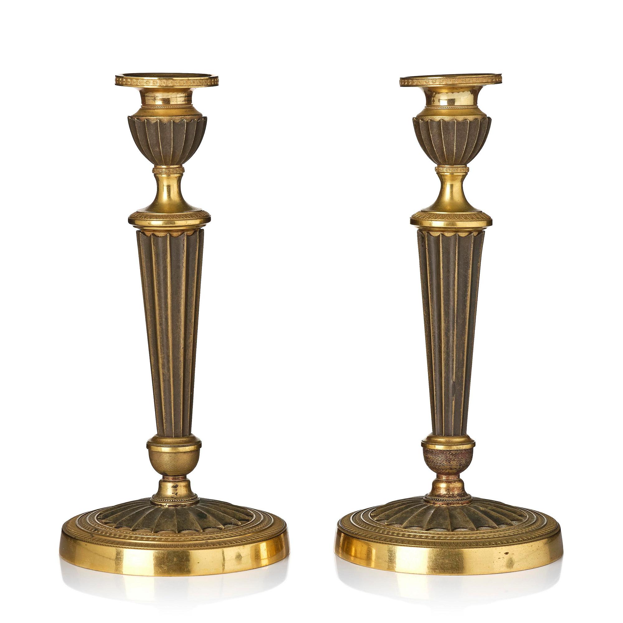 A pair of French Empire patinated and ormolu candlesticks, early 19th century.