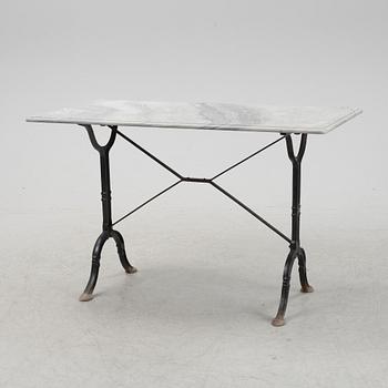 A cast iron garden table with a marble top, from around the year 1900.