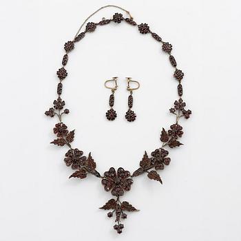 Garniture, necklace/bracelet and earrings in silver with garnets in the form of floral motifs, around the turn of the 20th century.