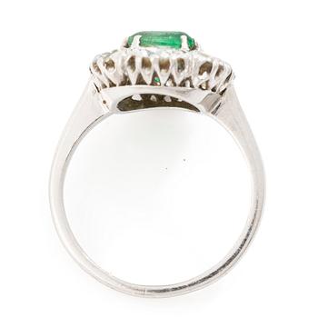 18K white gold ring set with a faceted emerald and round brilliant-cut diamonds.