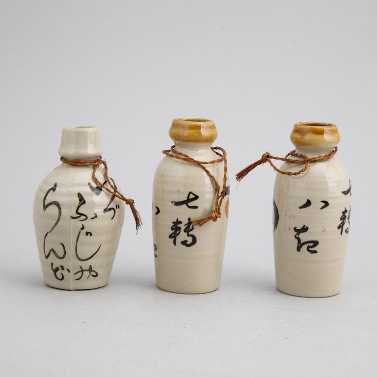 A group of twelve Japanese white glazed ceramic sake bottles, first half of the 20th century and mid 20th century.