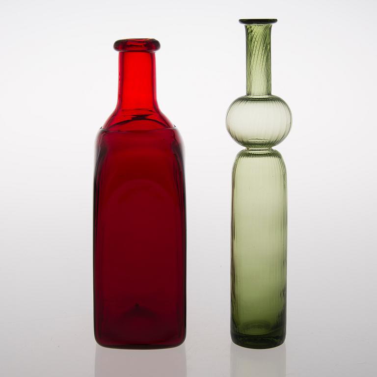 Two glass bottles. A green 'Neptuna' bottle designed by Nanny Still in 1964 and a red bottle from Riihimäen Lasi oy.