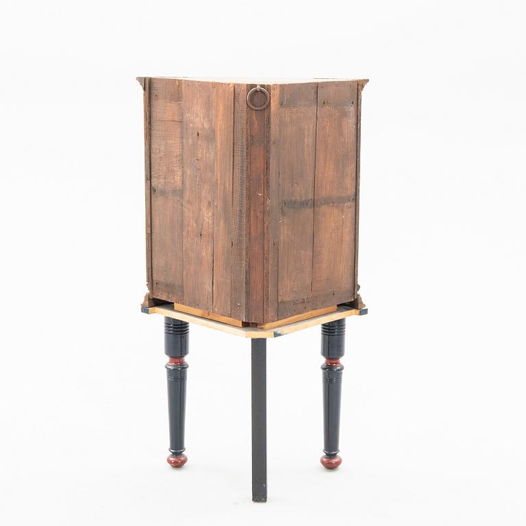 Corner cabinet on a legged stand dated 1810.