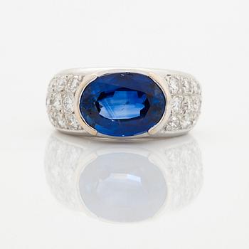 An 18K white gold ring set with an oval faceted sapphire and round brilliant-cut diamonds.