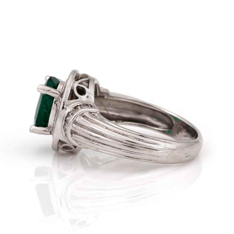 A ring with an oval, mixed-cut emerald and diamonds.