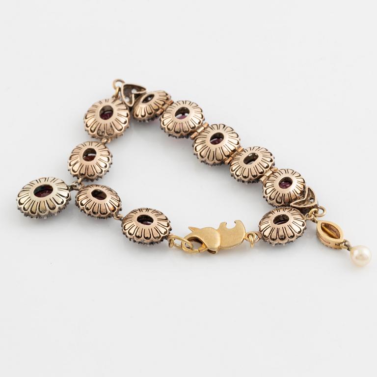 Bracelet with garnets and white stones, two charms, one eye enamel with brilliant cut diamonds, possibly oriental pearl.