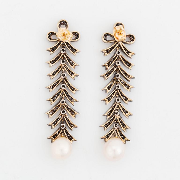 A pair of silver and 18K gold earrings with cultured pearls and set with eight-cut diamonds.