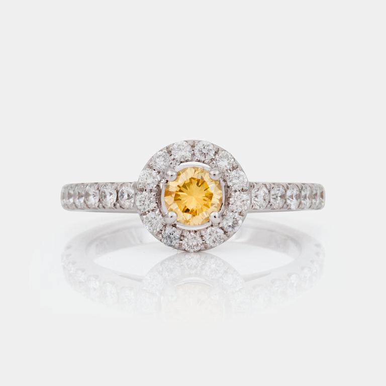 A fancy yellow brilliant-cut diamond, circa 0.36 ct, ring. Pavé-set colourless brilliant-cut diamonds.