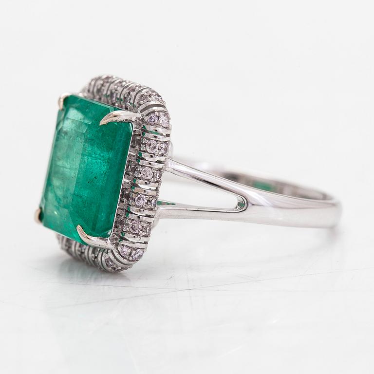 A 14K white gold ring, with an emerald approx. 5.21 ct and diamonds totalling approx. 0.23 ct, according to certificate.