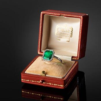 A platinum ring set with a Colombian step-cut emerald and old-cut diamonds in a fitted case from Cartier.