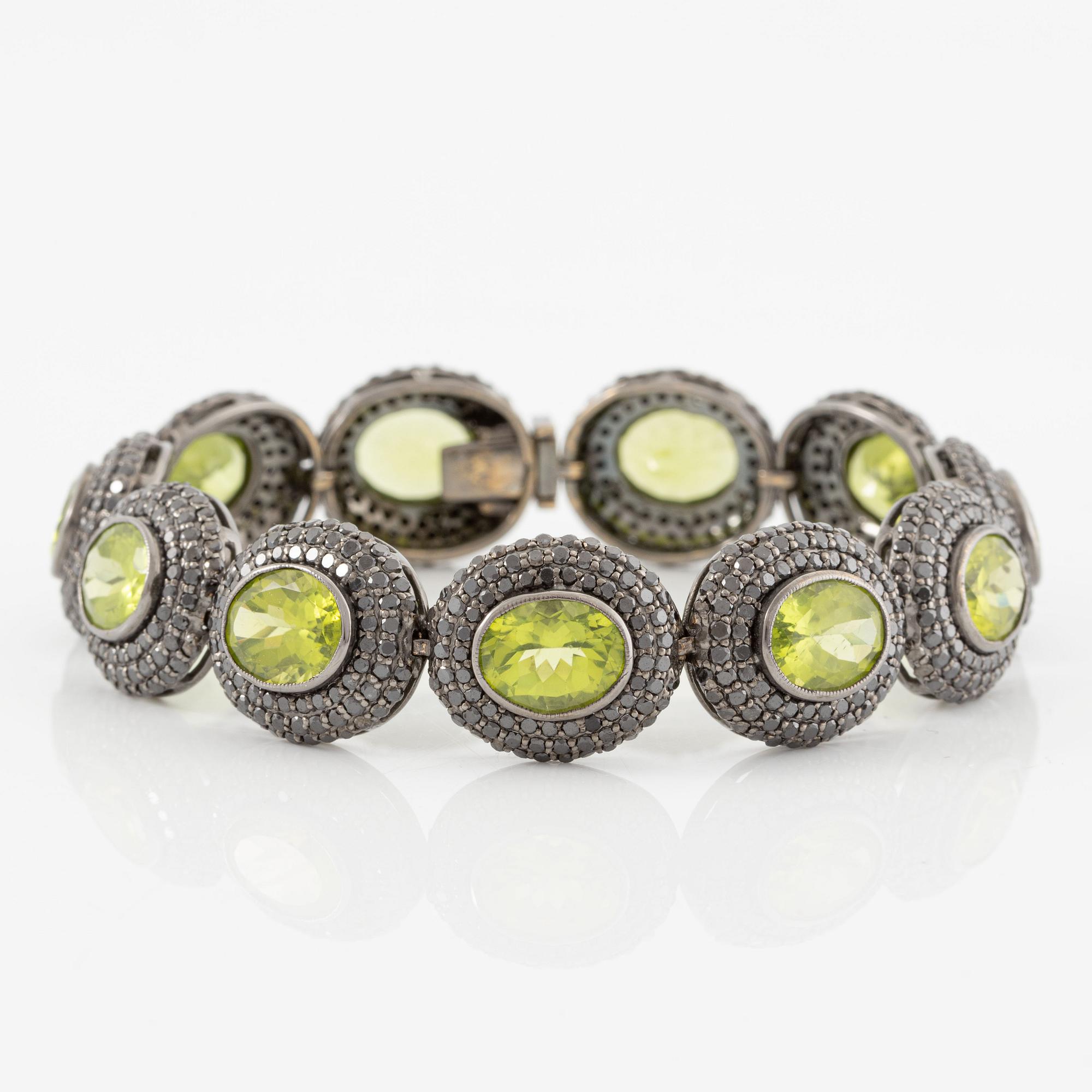 Bracelet in 18K gold with oval peridots and brilliant-cut black diamonds.