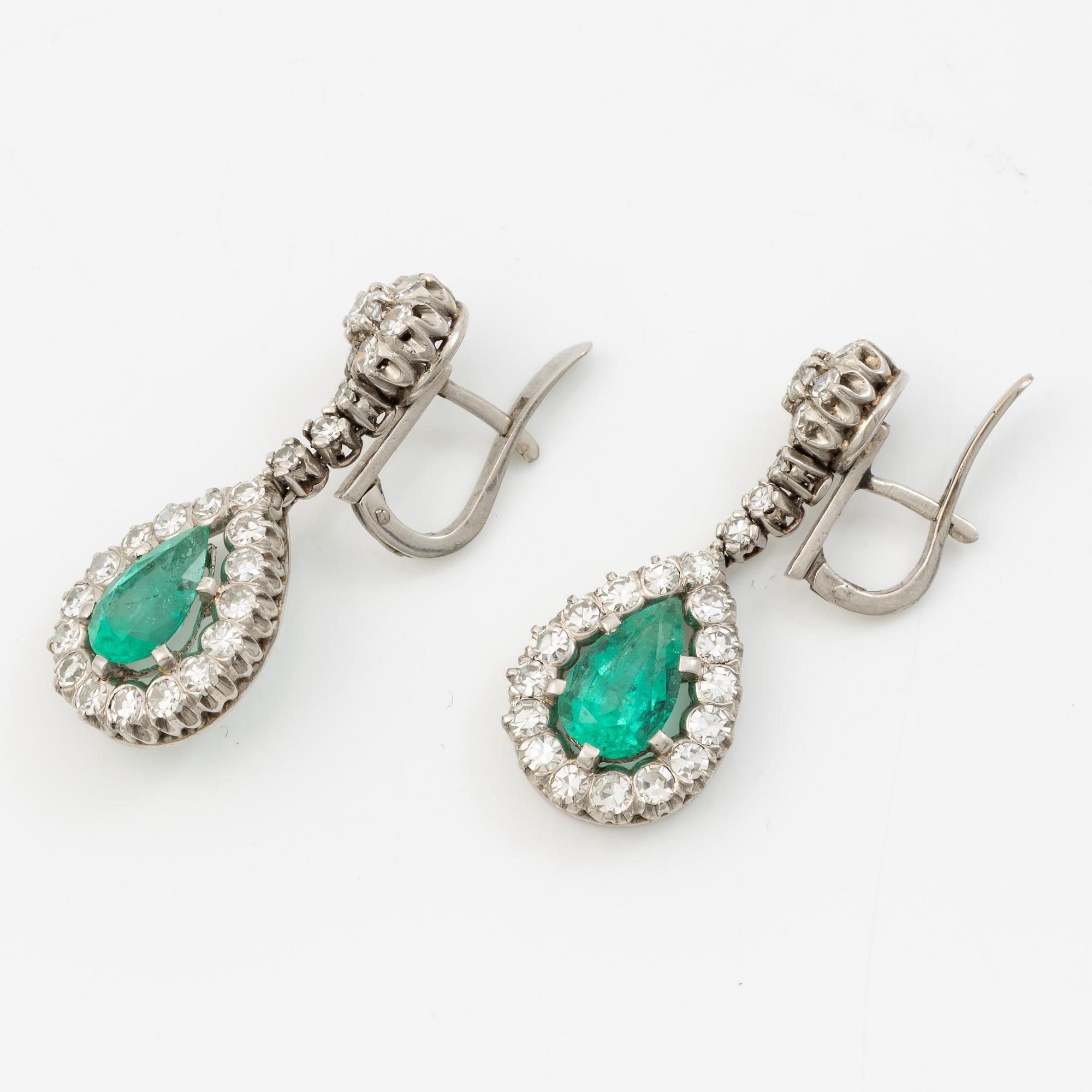 Earrings in platinum with drop-shaped emeralds and brilliant-cut and octagonal-cut diamonds.