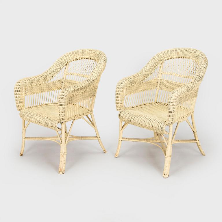 A mid-20th-century three-piece rattan furniture set including two armchairs, and a table.