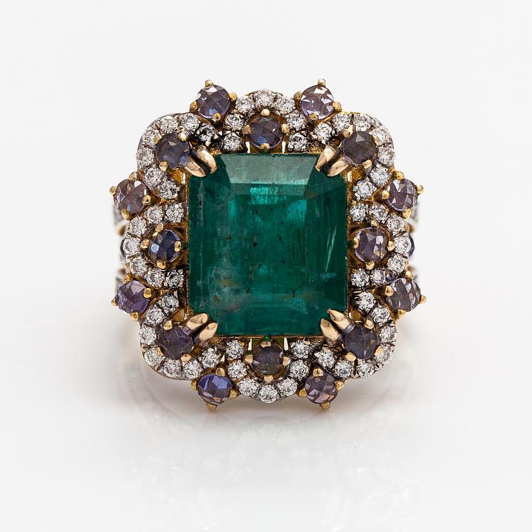 A 14k gold ring with an emerald ca. 6.39 ct, tanzanites and diamonds ca. 1.25 ct in total.