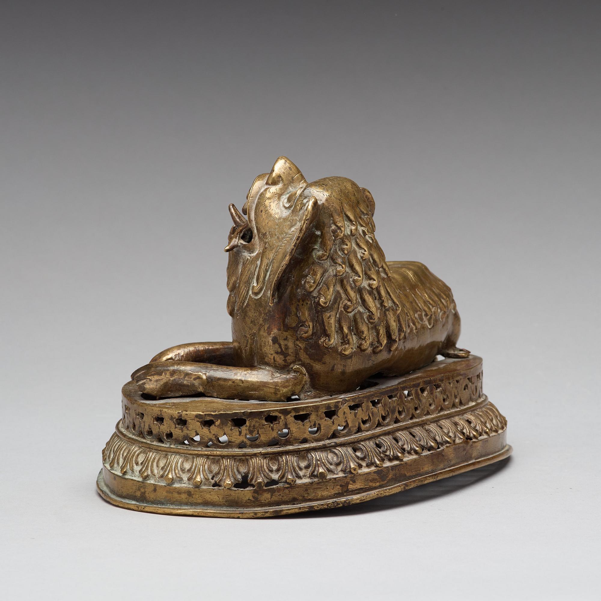 A copper alloy figure of a reclining buddhist lion, presumably 18th Century.
