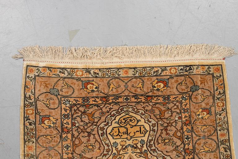 A rug, old silk Hereke, signed, ca 84,5 x 66 cm.