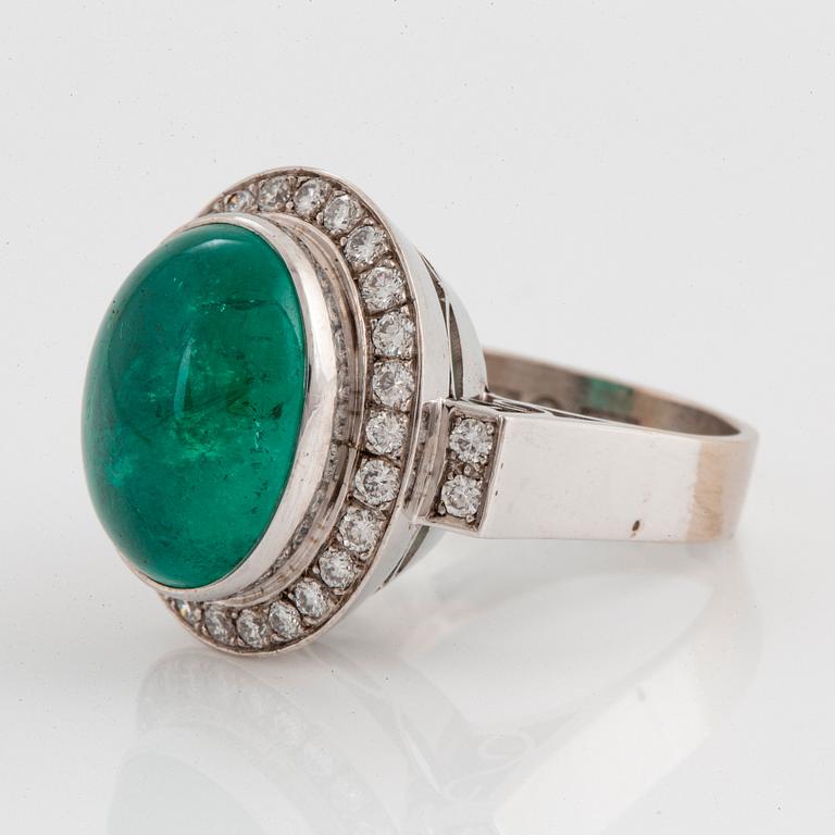 An 18K white gold ring set with a cabochon-cut emerald and round brilliant-cut diamonds.