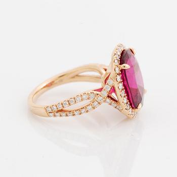 An 18K gold ring set with a faceted pink tourmaline and round brilliant-cut diamonds.