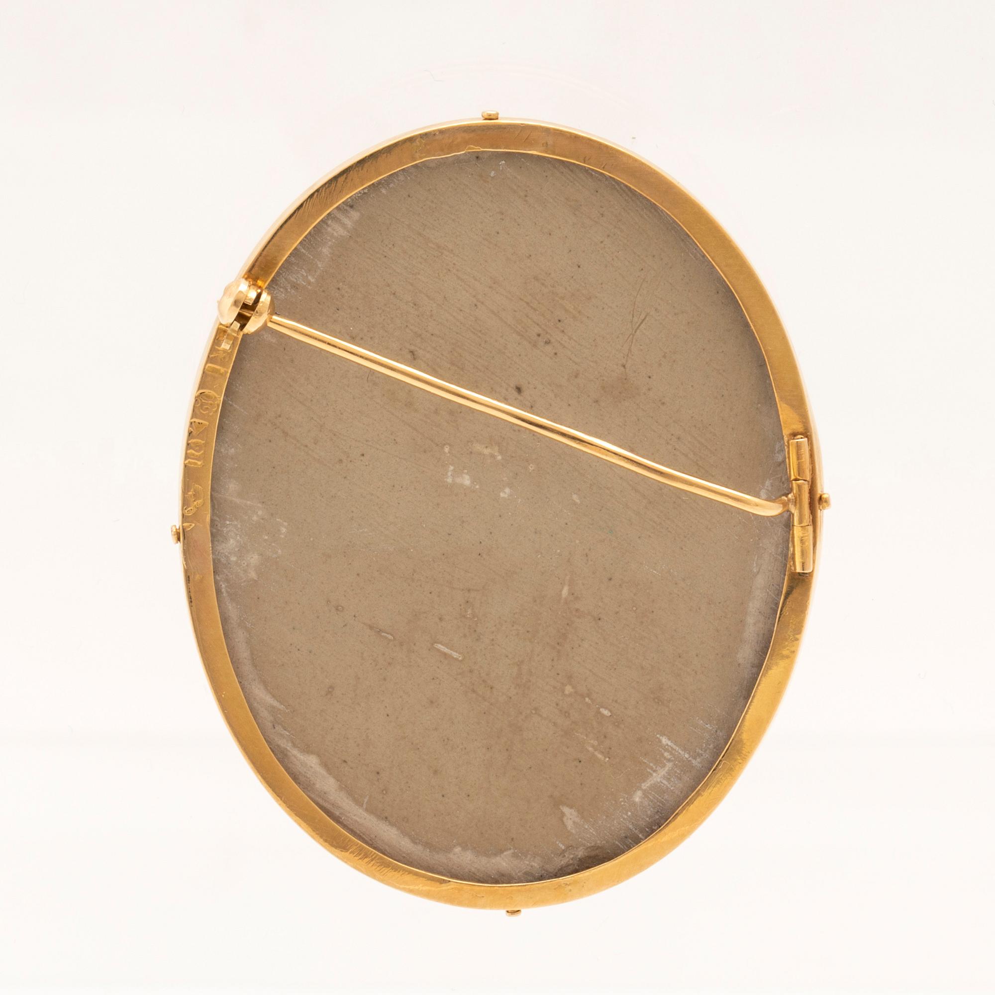 Brosch med lavakamé infattad i 18K guld.