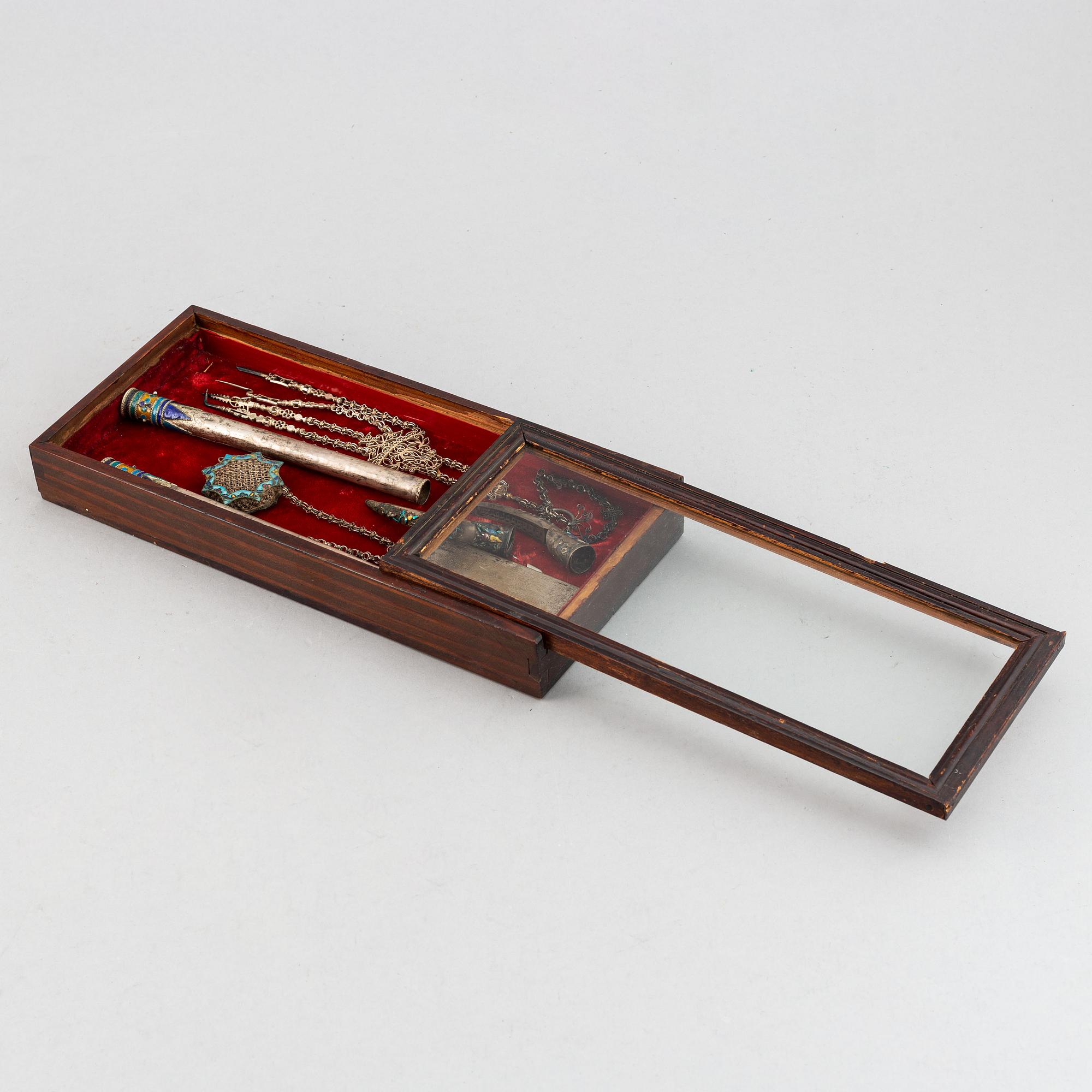 A box with nail covers, cigarett holders, a card, a pendant and some tools, China, circa 1900.