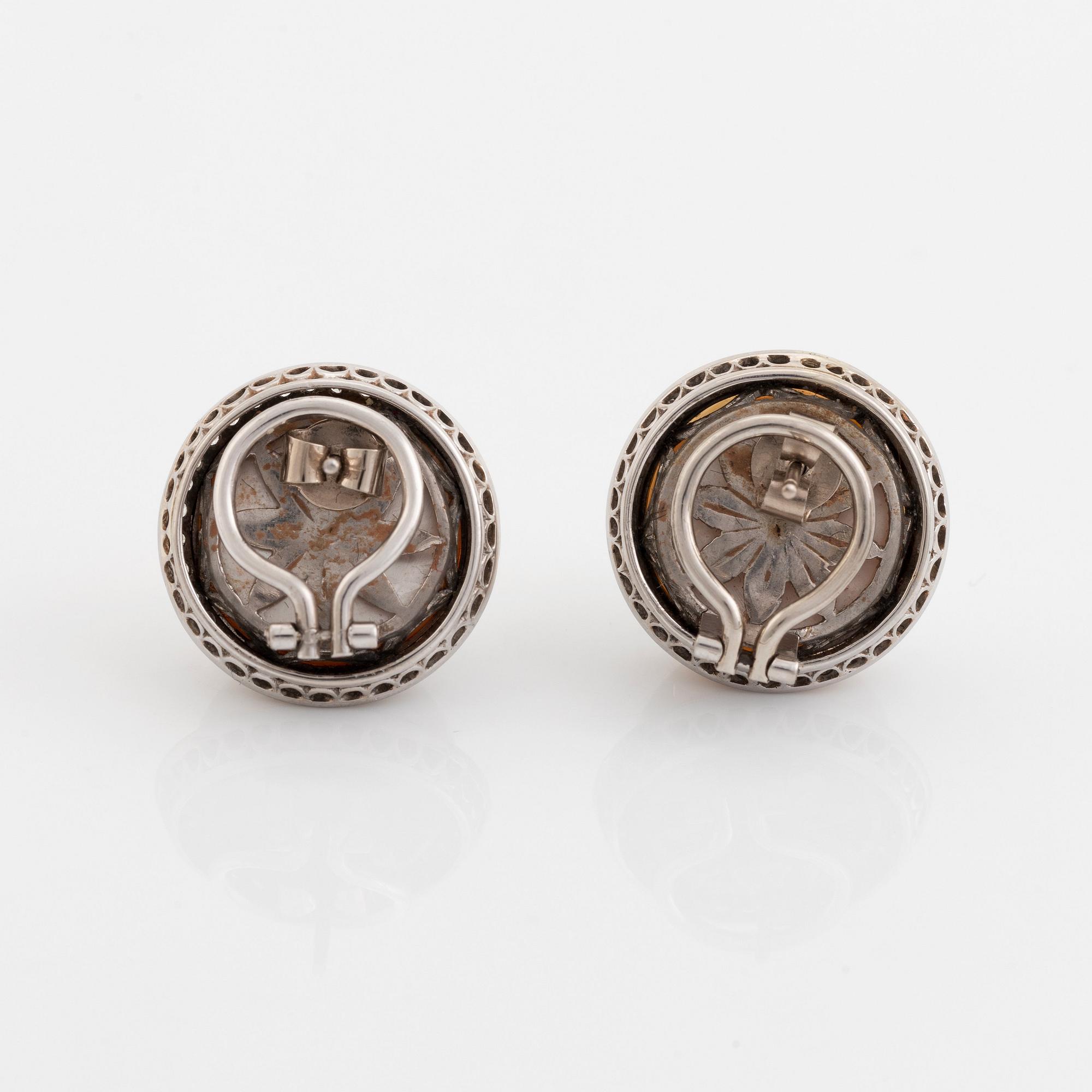 A pair of 18K white gold earrings set with cultured mabe pearls and round brilliant-cut diamonds.
