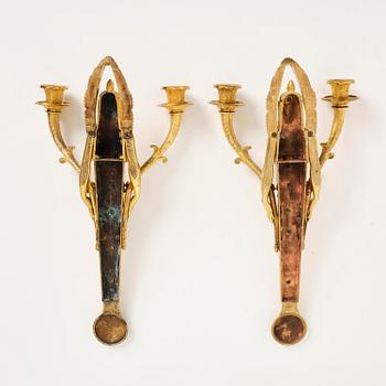 A pair of French Empire two-branch ormolu wall lights, early 19th century,.