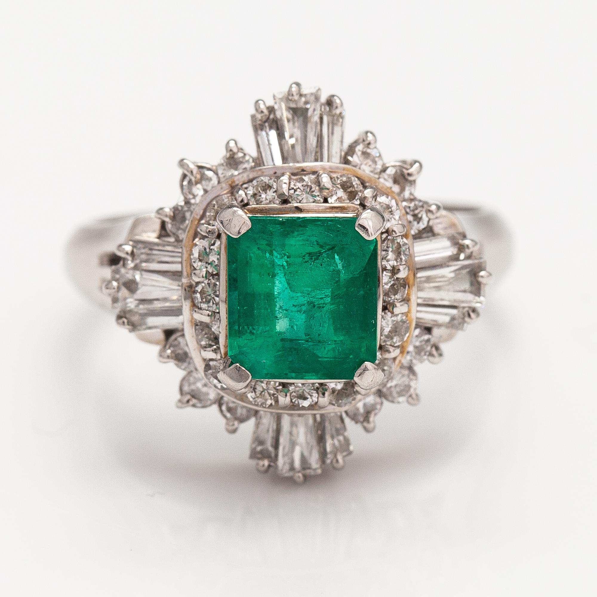 A platinum ring with a ca. 1.15 ct emerald and ca. 1.00 cts of diamonds in total.