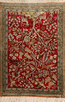 A silk rug from Qum, around 75 x 54 cm.