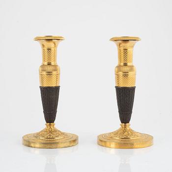 A pair of French Empire gilt and patinated bronze candlesticks, circa 1820's.
