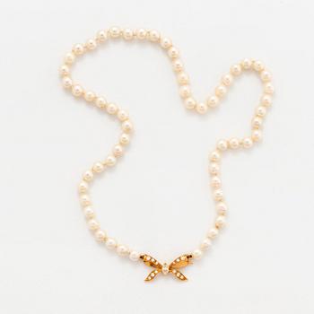 A cultured pearl necklace with a bow clasp in 18K gold set with round brilliant-cut diamonds.