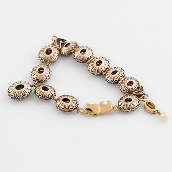 Bracelet with garnets and white stones, two charms, one eye enamel with brilliant cut diamonds, possibly oriental pearl.