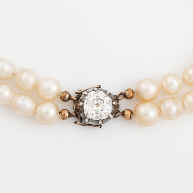 A two strand natural pearl necklace with a silver  clasp set with an old-cut diamond.