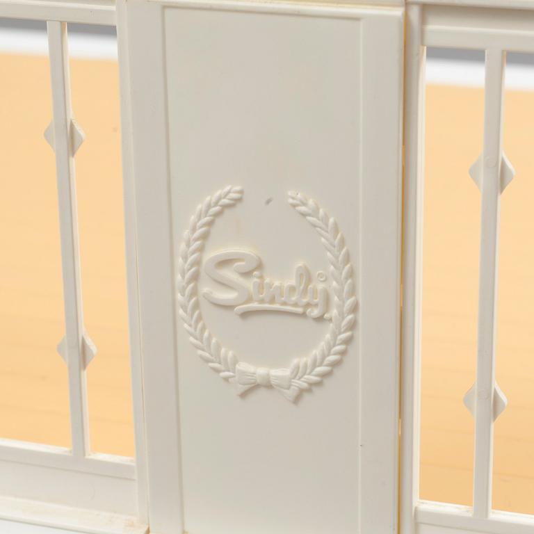 A plastic doll's house with six dolls, furniture and clothes, 20th century.