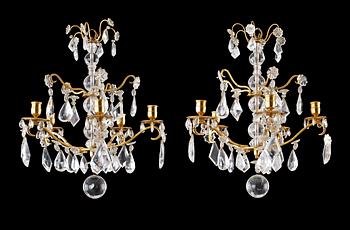 A pair of Baroque style four-light rock crystal chandeliers.