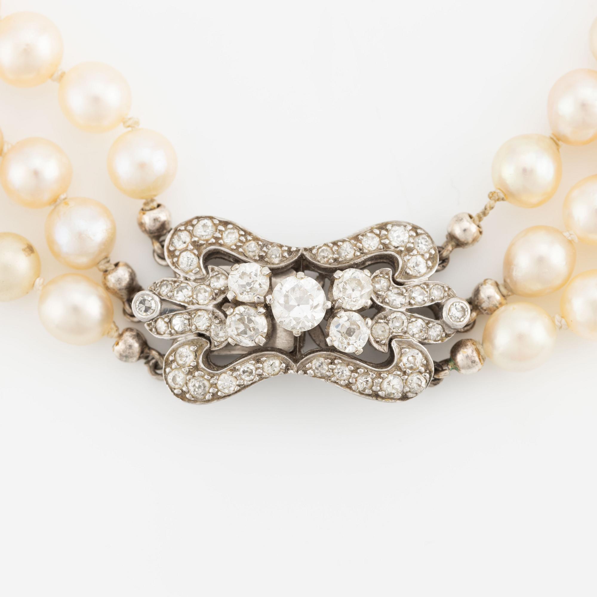 A three-strand cultured pearl necklace with an 18K white gold clasp with round brilliant-cut diamonds.