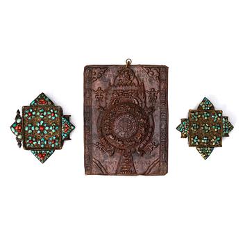 892. A copper reousse placque and two Tibetan pendants, 19th /20th Century.